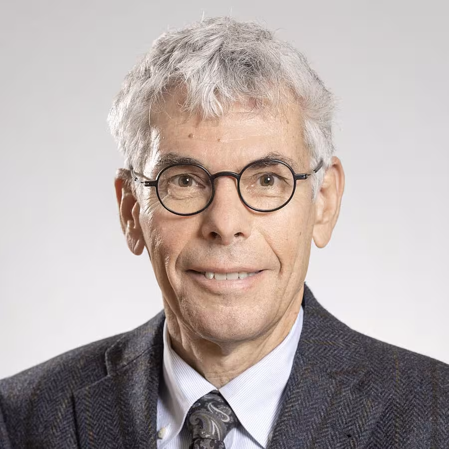 Portrait en buste de Stefan Maul. Il porte des lunettes rondes, a les cheveux courts gris et sourit à la personne qui le regarde. Il porte une chemise, une cravate et une veste de costume.